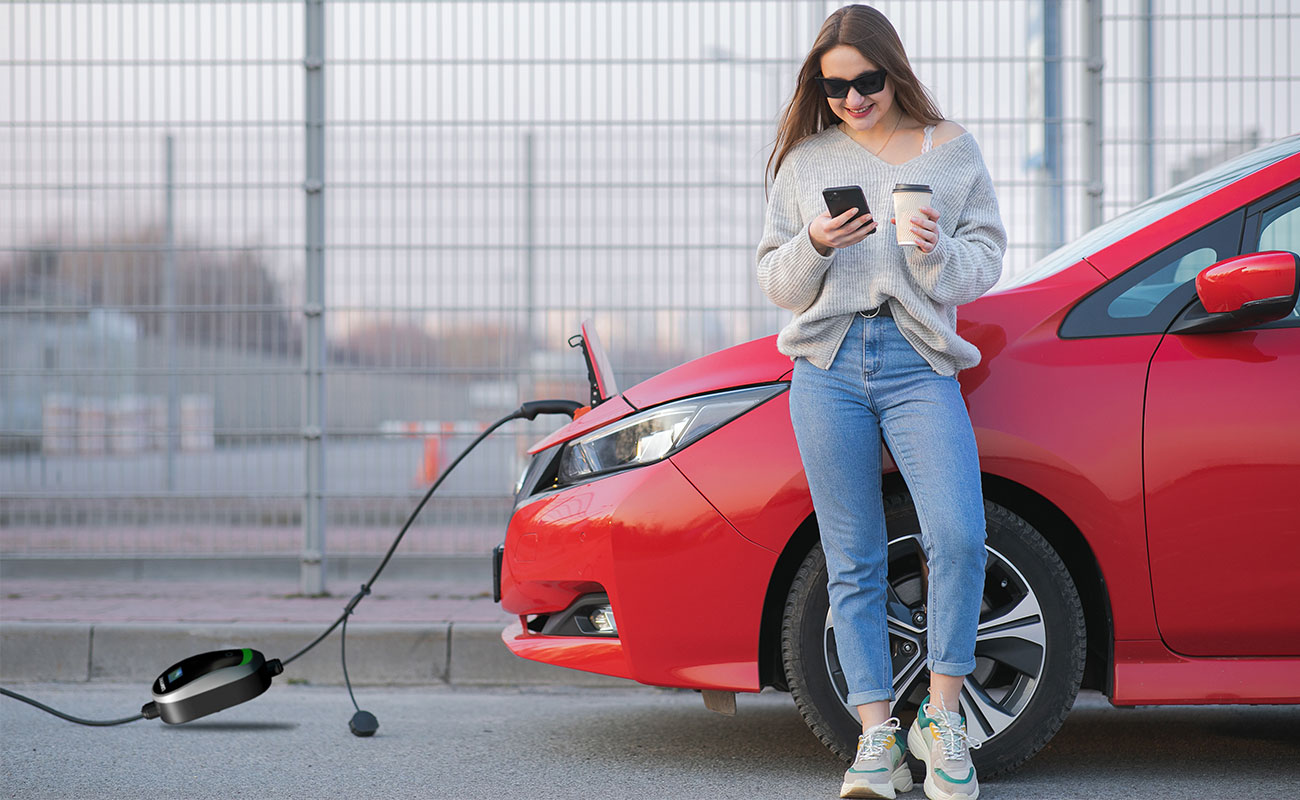 A woman using a portable car charger for her electric car during a road trip.