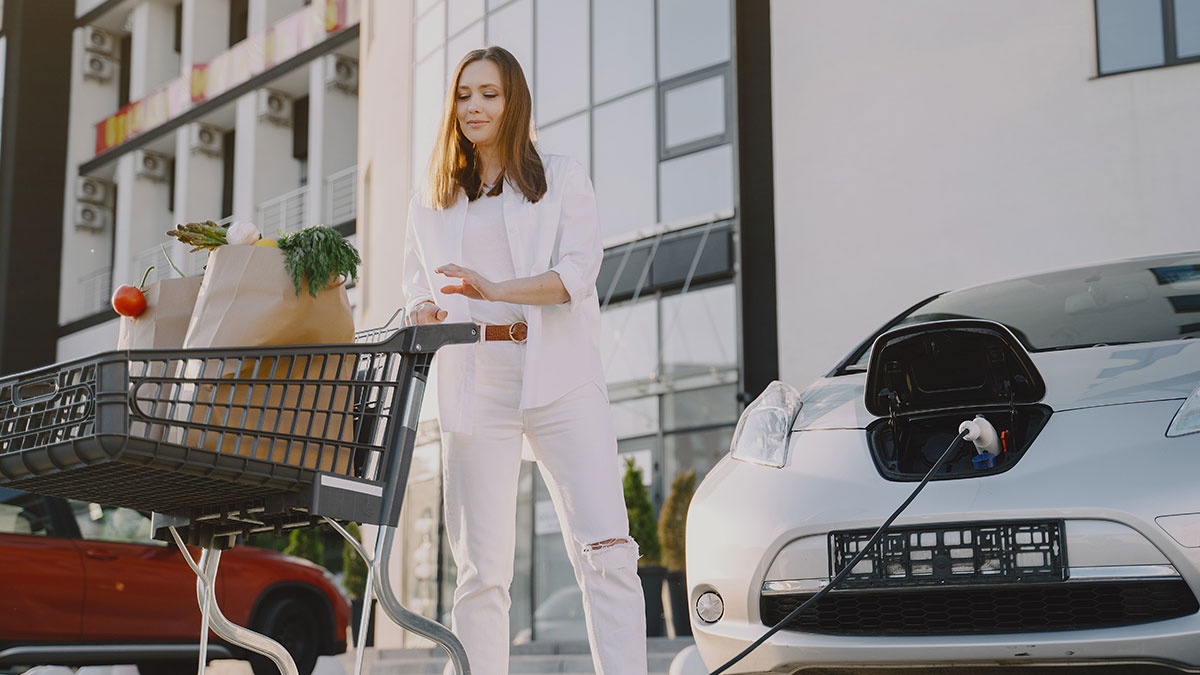 A woman does her shopping while her car is charging