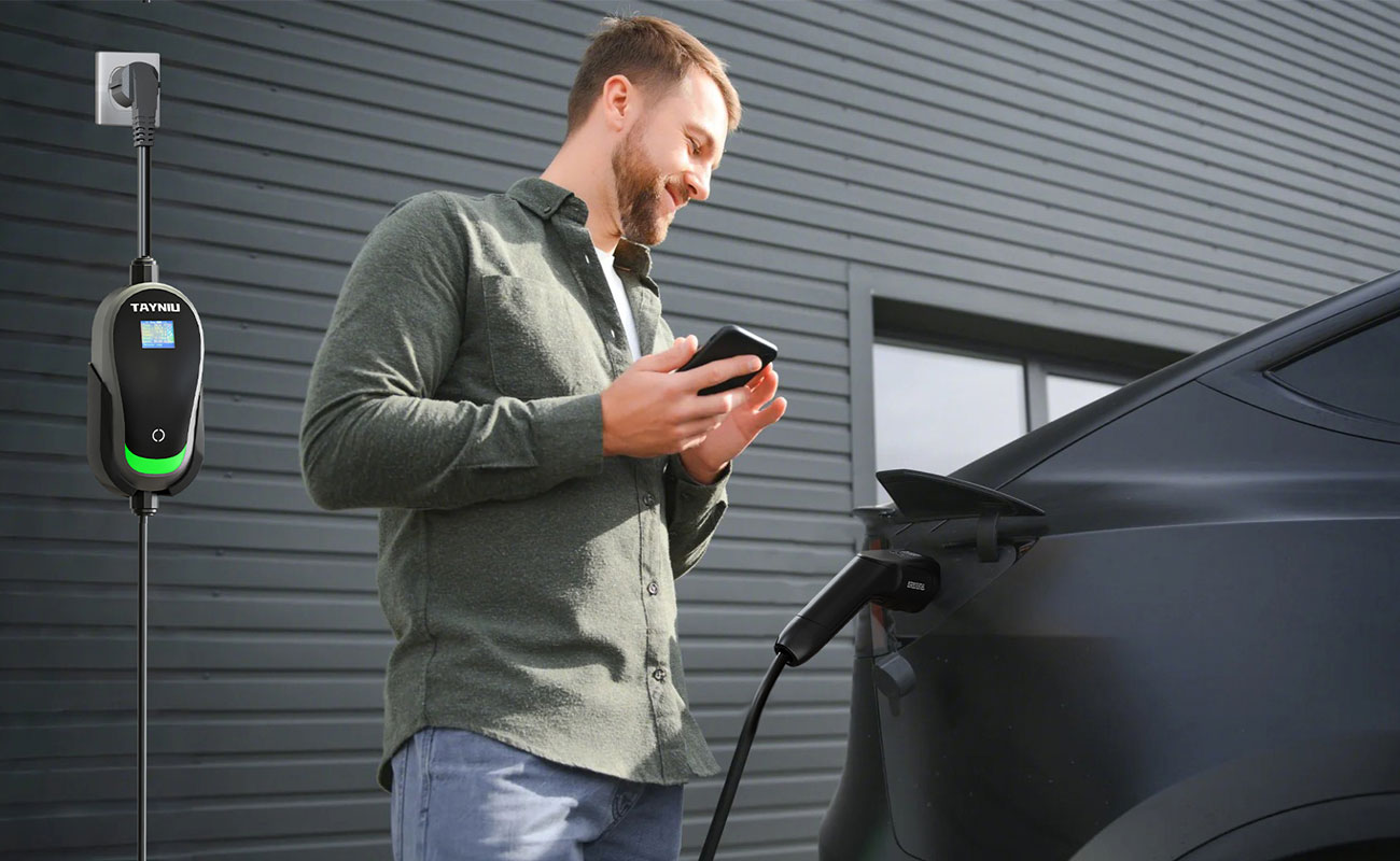 A man is using a portable ac charger to charge his electric car