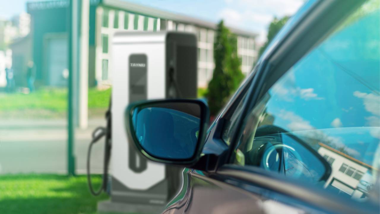 A black electric car parked in front of the dc charger