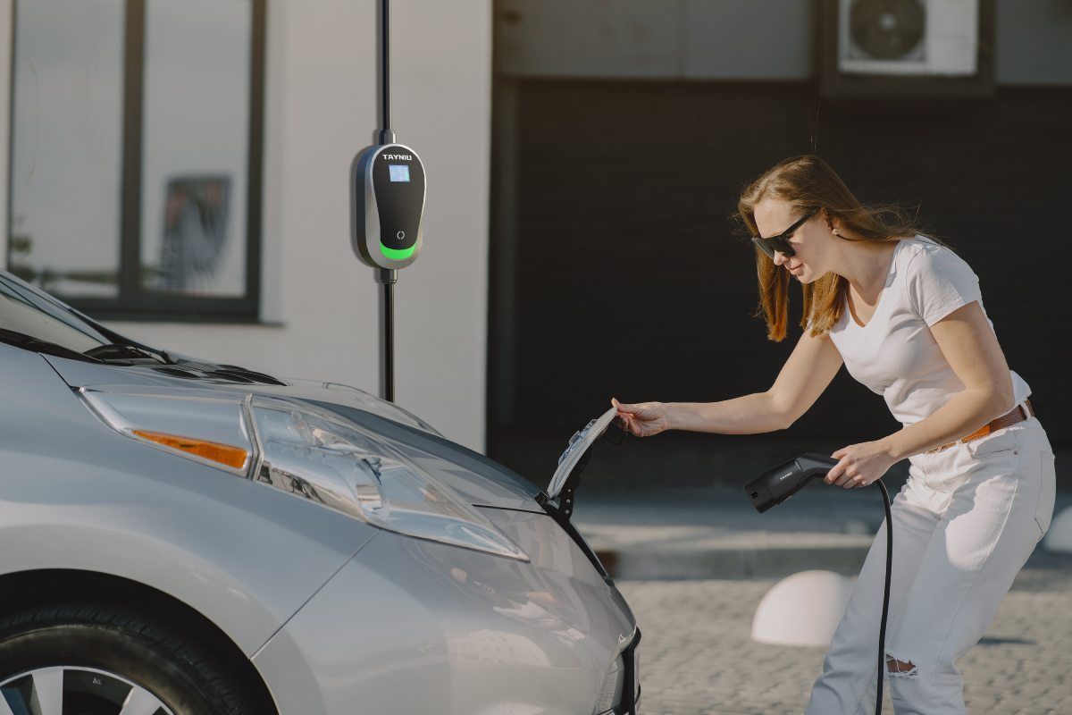 A woman is using a portable electric car charger to charge her car at a hotel.