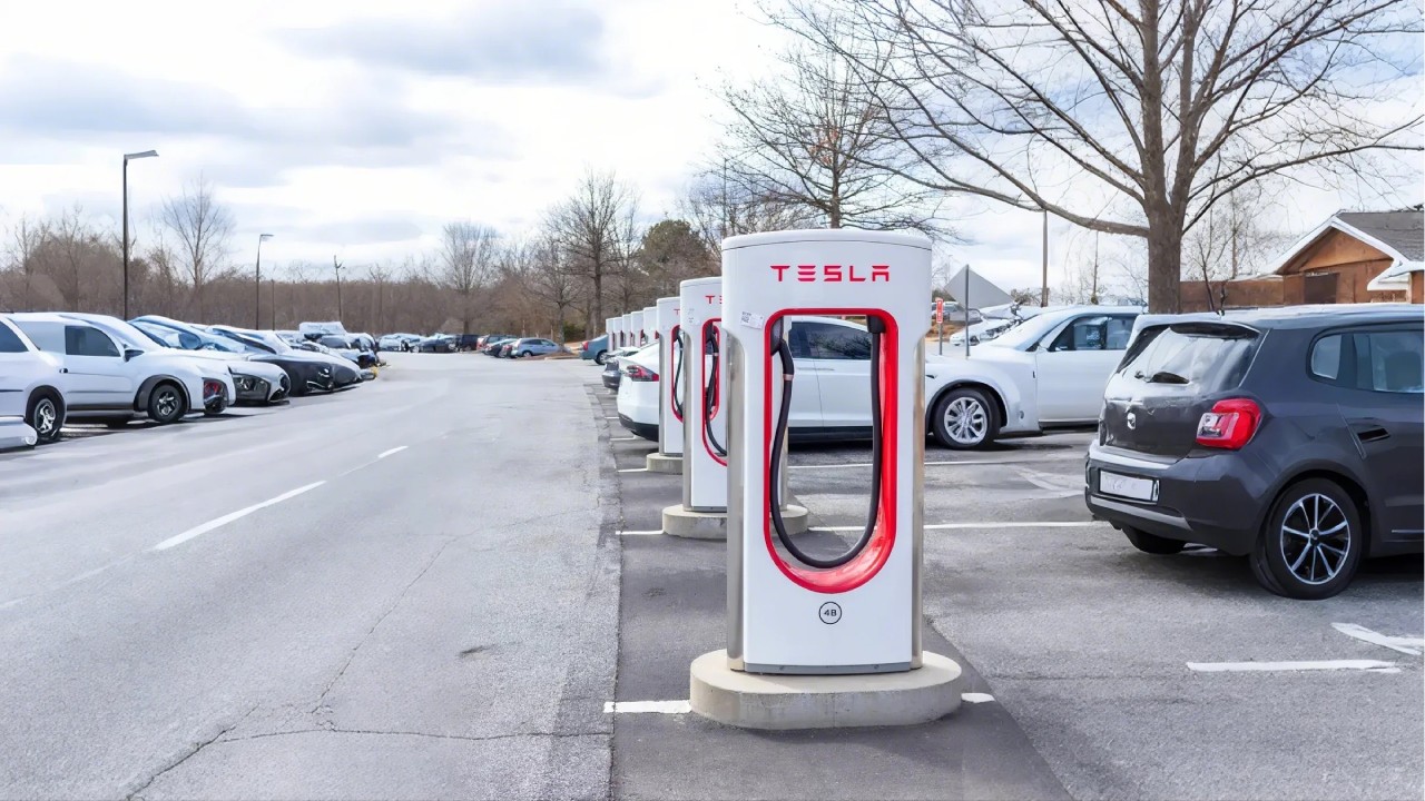 Tesla Supercharger stations in a parking lot, highlighting the comparison between J1772 chargers and Tesla chargers.