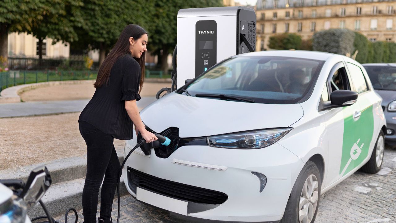 A woman using a Tayniu commercial electric car charger to charge her EV in an urban environment.